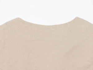 Close-up of beige linen fabric texture and neckline detail of a beaded vest set
