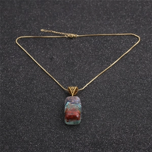 Detailed macro view of an Orgonite rectangular pendant with colorful stones on golden chain