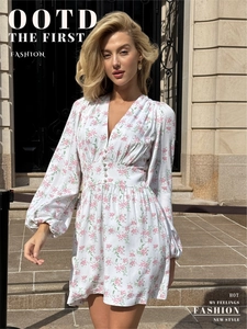 Detail of white floral V-neck dress featuring button accents and fitted waistline