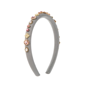 Serre-tête rembourré gris avec cristaux roses, perles et trèfles dorés sur fond blanc