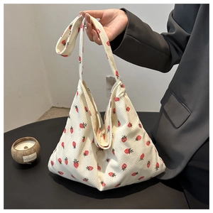 Detail of strawberry print corduroy tote bag showing soft texture and shoulder straps