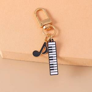 Macro detail of music keychain featuring a gold spring clasp, black note and piano key charms