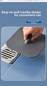 Detail showing hand lifting a gray silicone drain cover by its handle over a metal grate