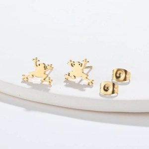 Detailed close-up of polished gold frog earrings with butterfly backings on a white surface
