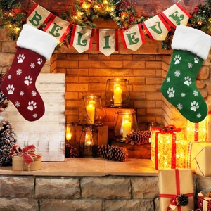 Detailed view of red and green embroidered paw print stockings on a festive mantel