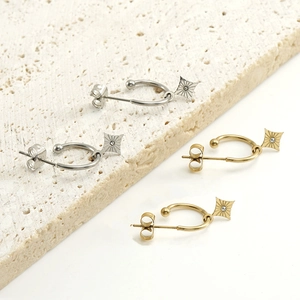 Detail von C-förmigen Ohrringen in Gold und Silber mit Diamant-Sternenanhängern