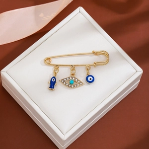 Detailed view of evil eye brooch with fish charm and blue rhinestones on jewelry box