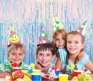 Iridescent foil fringe curtain backdrop and colorful party hats worn by smiling children