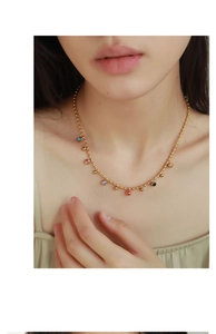 Close-up of gold beaded necklace with colorful 18k plated enamel bean charms on a model