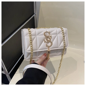 Close-up of white quilted crossbody bag featuring a gold S logo and fringe detail
