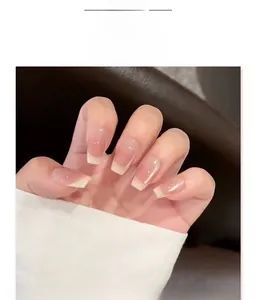 Close-up of French style press-on nails with nude pink base and white tips on hands