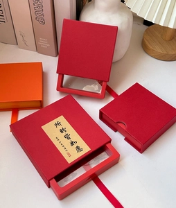 Detalle de cajas de regalo chinas rojas y naranjas con cordón y texto en pan de oro