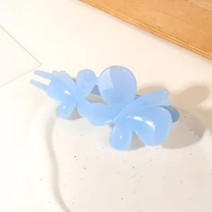 Detail of light blue butterfly hair clip with resin texture on white ceramic tray