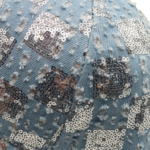 Macro view of light blue washed denim with silver sequins in a checkerboard pattern