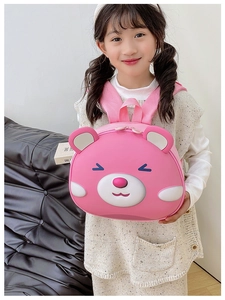 Pink cartoon bear hardshell backpack for kids shown on child in home setting