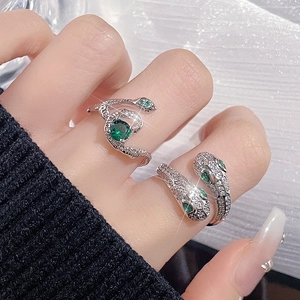 Elegant silver snake rings with green zircon stones worn on hand with starry background