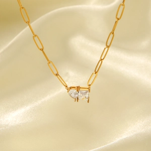 Detail of 18k gold paperclip chain featuring square and heart zircon double pendants