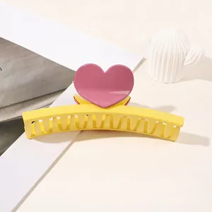 Detail of large yellow hair claw clip with pink purple heart decoration for thick hair
