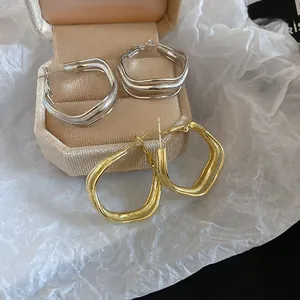 Detail of irregular wave layered metal hoop earrings in gold and silver finish