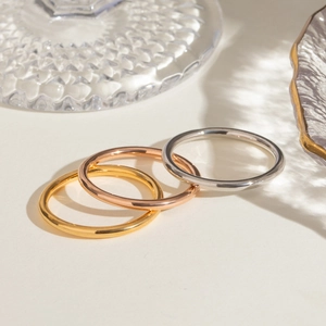 Close-up of three polished rings in gold, rose gold, and silver on a minimalist background