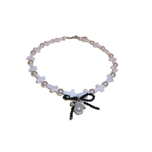 Cross resin necklace with crystal bows and pearls in a minimalist flat lay
