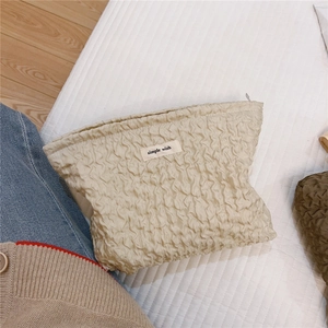 Détail de la trousse de maquillage beige plissée ondulée avec étiquette simple wish