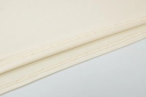 Detailed macro view of high-density cream jersey fabric with reinforced stitching