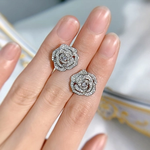 Close-up of silver rose stud earrings with shimmering inlaid crystals on a hand