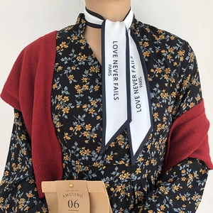 Detail view of a French vintage scarf tied on neck with LOVE NEVER FAILS PARIS text