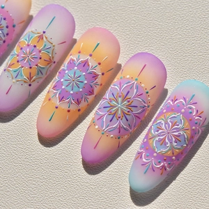 Détail de faux ongles mats avec motifs mandala bohèmes aux couleurs dégradées