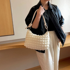 Dettaglio della borsa a tracolla bianca a bolle con manico annodato alla moda