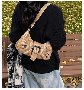 Detail of khaki PU leather crescent bag with metal buckle in an outdoor park setting