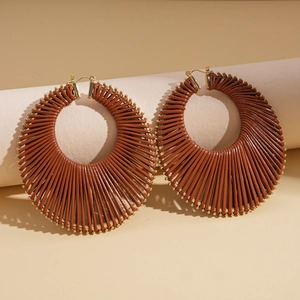 Detailed shot of brown woven hoop earrings with golden beads in Bohemian style