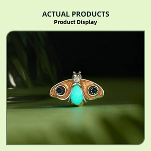 Close-up of moth charm with luminous body, brown wings, and blue gemstone details