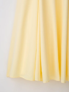 Vista dettagliata del tessuto in chiffon giallo con trama plissettata e drappeggio