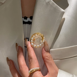 Macro shot of a 24k gold-plated pearl brooch and matching ring on elegant fabric