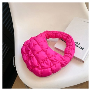 Close-up of a pink quilted cloud bag in hobo style on a white chair with books
