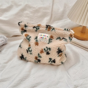 Close-up of floral plush makeup bag with sheepskin fleece texture and fabric label