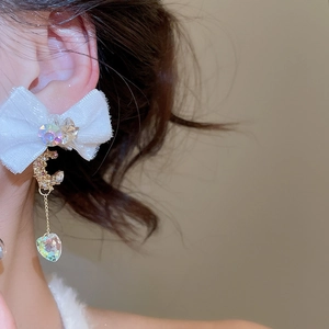 Close-up of fabric bow earrings with crystal heart pendant on model for elegant look
