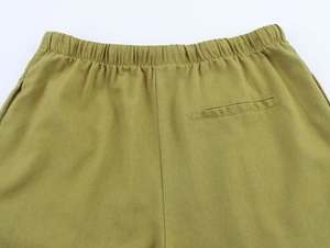 Detail of elastic waistband and welt pocket on olive green linen trousers fabric