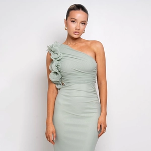 Détail d'une robe asymétrique vert clair avec fleur en 3D volantée et tissu mesh plissé
