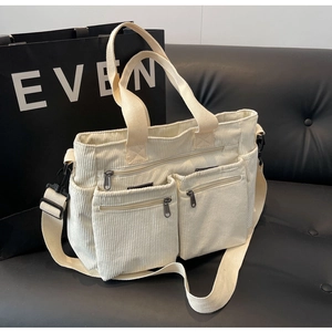 Detail of off-white corduroy shoulder bag showing multi-pocket design and strap