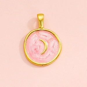 Macro detail of round alloy pendant featuring pink enamel finish and golden crescent moon charm