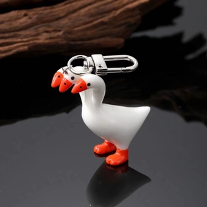 Macro shot of creative white goose pendant with bright orange beak and silver metal keychain