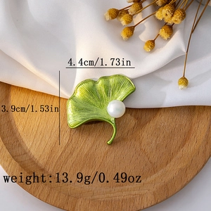 Macro shot showing green ginkgo leaf brooch dimensions of 4.4cm by 3.9cm with a white pearl