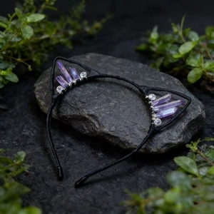 Detailed view of handmade black metal cat ear headband with raw purple crystals on a stone