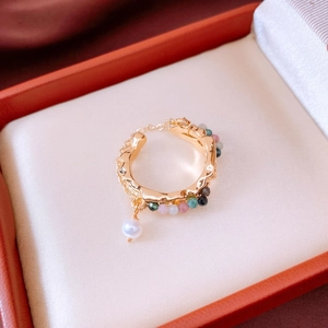 Detail of 18k gold plated wave ring with multicolored beads and a dangling pearl charm