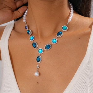 Vintage necklace with blue gemstones and pearls shown on a model neck in a Y-shape