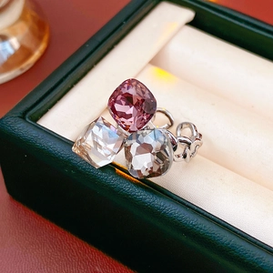 Macro detail of a silver-toned open ring featuring three colorful square-cut crystals