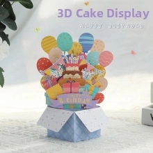 Macro shot of a 3D pop-up birthday card featuring a paper cake, balloons and gift boxes
